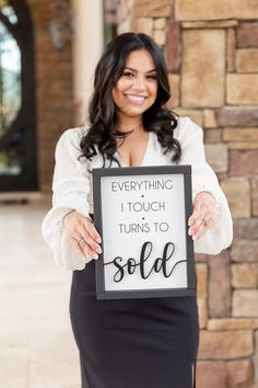 a woman holding up a sign that says everything i touch turns to sold