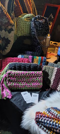 several crocheted purses are on display in front of other bags and hats