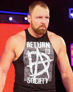 a man with a beard standing in front of a red and blue background wearing a black tank top