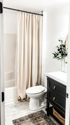 a white toilet sitting next to a bath tub in a bathroom under a shower curtain