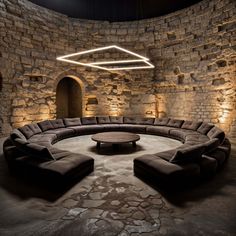 a circular couch sitting in the middle of a room with stone walls and flooring