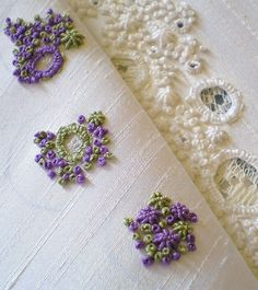 three pieces of crocheted fabric with flowers on them, one is white and the other is purple