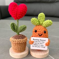 two small crocheted carrots sitting next to each other on top of a table