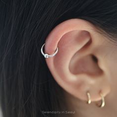 a woman's ear is shown with two small hoops