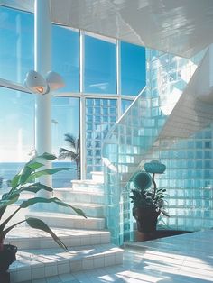 an indoor stair case with glass blocks and plants in the foreground, overlooking the ocean