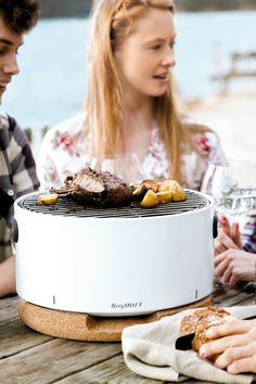 three people sitting at a table with food and wine