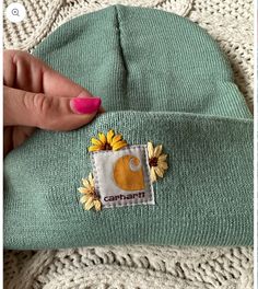 someone is showing off their green beanie with sunflowers on the front and bottom