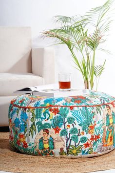 a colorful ottoman sits in the middle of a living room with a plant on it