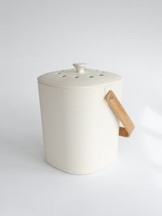 a white canister with a wooden handle and lid is shown on a white background