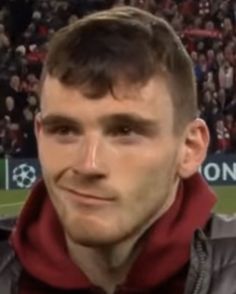 a man is standing in front of a crowd at a soccer game with his head turned to the side