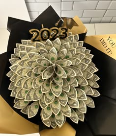 a pile of money sitting on top of a graduation cap with the year 2013 written on it