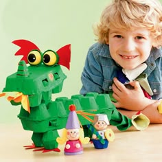 a little boy laying on the floor next to some toy figurines and a green dragon