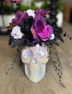 a skull vase with flowers in it sitting on a table