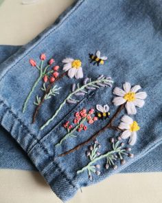 a pair of jeans with embroidered flowers on them