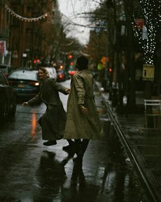 two people walking down the street in the rain