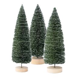 three small evergreen trees are on display in the shape of wooden bases with snow flakes all around them