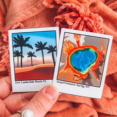 two cards with palm trees on them are held in someone's hand and the one has a pearl brooch