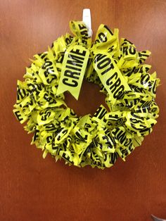 a yellow wreath with black letters on it and a white ribbon hanging from the front