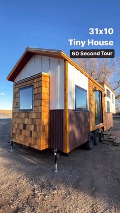 the tiny house is on display in front of a blue sky and brown dirt ground