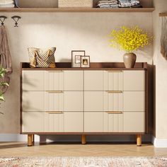 a white dresser sitting next to a yellow vase on top of a wooden shelf in a living room