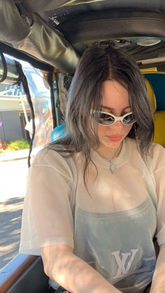 a woman sitting in the back of a bus wearing sunglasses