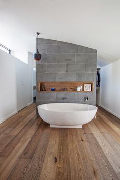 a large white bath tub sitting on top of a wooden floor