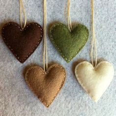 four heart shaped ornaments hanging from strings on a white carpeted floor, one is green and the other is brown