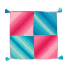 a pink, blue and green square with tassels on the sides is shown