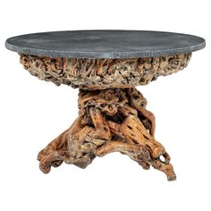 a table made out of drift wood and stone top with an iron plate on the base