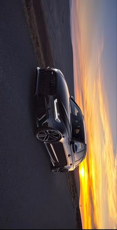 an aerial view of a car driving on the road near the ocean at sunset or sunrise