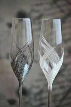 two wine glasses sitting next to each other on top of a wooden table with silver foil