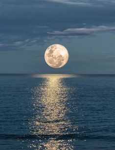 the full moon shines brightly in the sky over the ocean as it reflects on the water