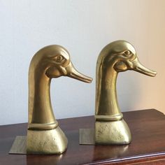 two brass ducks are sitting on a wooden table