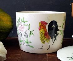 a white bowl sitting on top of a wooden table next to an orange and green pumpkin