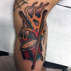 a man with a tattoo on his leg has a drum and bat in flames coming out of it