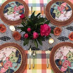 the table is set with plates, silverware and pink flowers