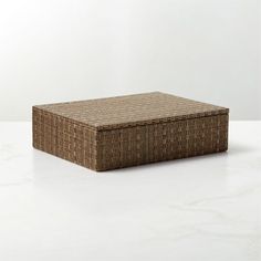 a square wicker box sitting on top of a white counter next to a wall