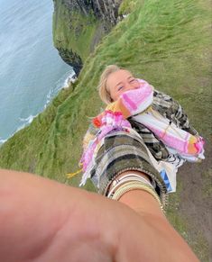 a woman is taking a selfie on the edge of a cliff