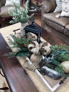 a coffee table with christmas decorations on it and a lantern in the centerpieces