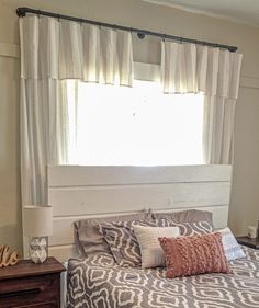 a bed sitting under a window next to a night stand