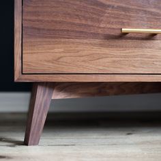 a close up of a drawer on a wooden table with wood grained finish and brass handles