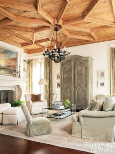 a living room filled with furniture and a chandelier hanging from the wooden ceiling