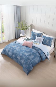 a bed with blue and white comforters in a bedroom next to a window,