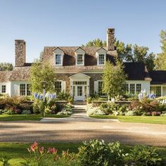 a large white house surrounded by trees and flowers