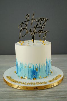 a birthday cake with blue and gold frosting on a white plate that says happy birthday