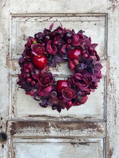 an old door with a wreath made out of flowers and apples