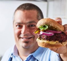 a man holding up a large hamburger in his hand