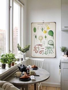 a kitchen with a table and some potted plants on the window sill next to it