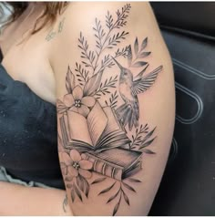 a woman with a tattoo on her arm has a book and flowers in the background