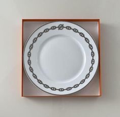 an empty white plate in a box with a chain around the rim and bottom edge